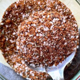 Close-up of a spoonful of spice blend displaying various textures, colors, and ingredients.