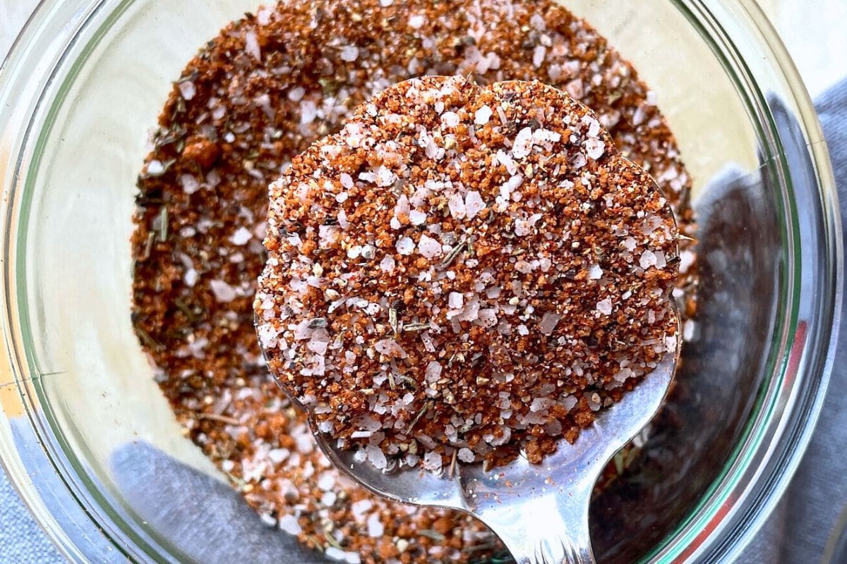 Close-up of a spoonful of spice blend displaying various textures, colors, and ingredients.