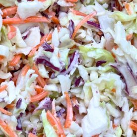 A vibrant close-up of a colorful coleslaw mixture featuring finely shredded cabbage and carrots.