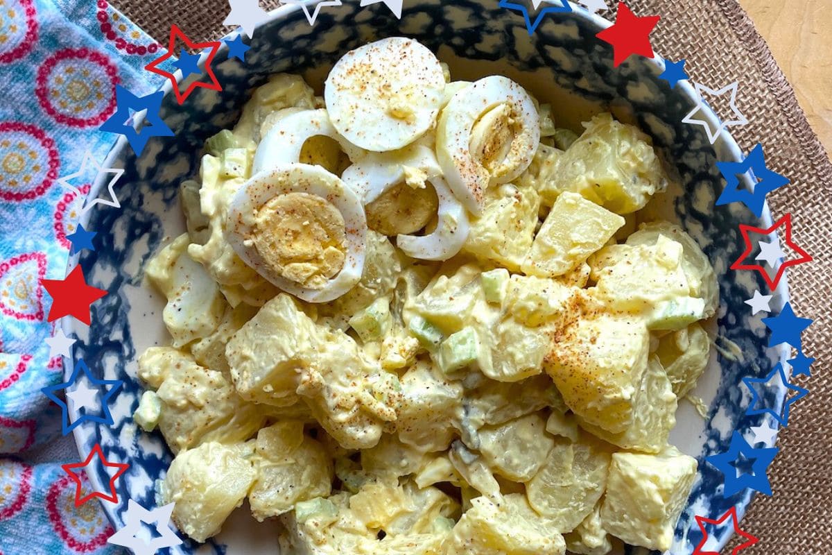A colorful bowl of potato salad topped with sliced hard-boiled eggs and sprinkled with seasoning, set against a backdrop of decorative stars.