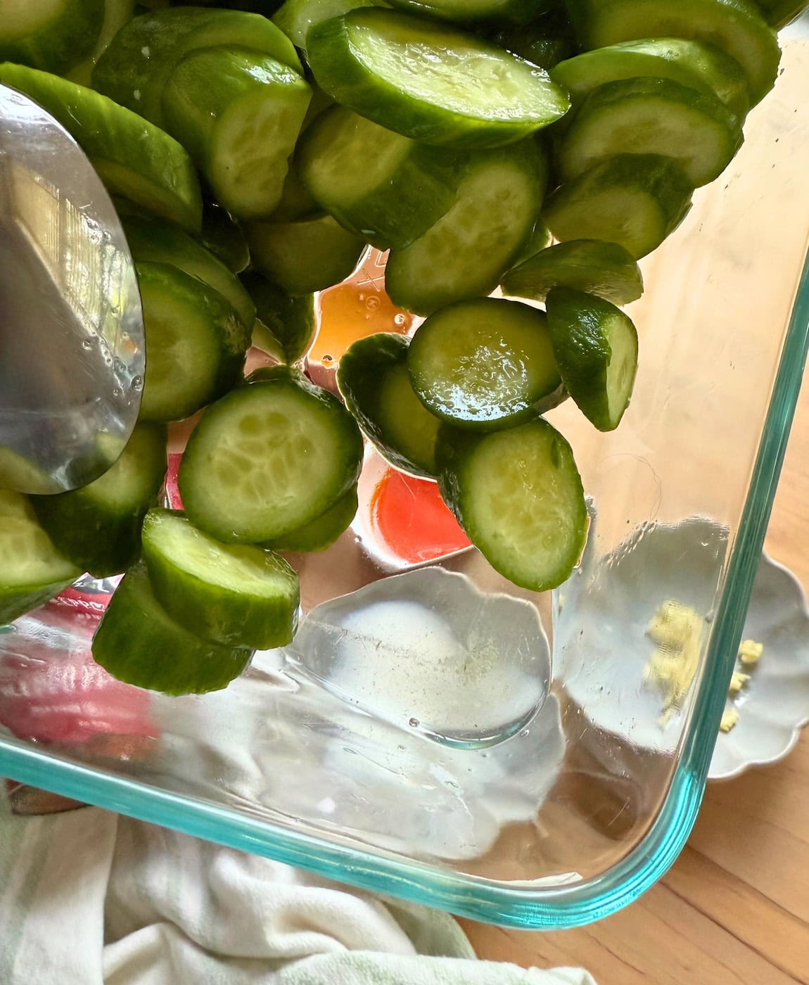 A close-up view of cucumber slices in a glass bowl after being salted.
