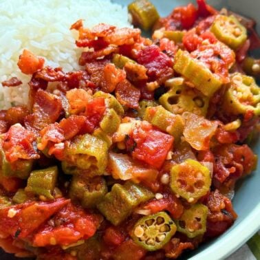 A close-up of a plate featuring stewed okra and tomatoes alongside a serving of fluffy white rice.