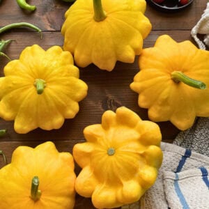 A vibrant arrangement of yellow summer squash on a wooden surface, showcasing their unique shapes and textures.