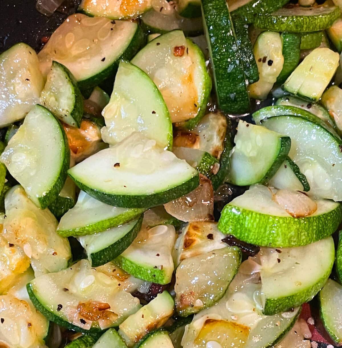 A close-up view of sautéed zucchini slices intermixed with caramelized onions, showcasing a vibrant mix of colors and textures.