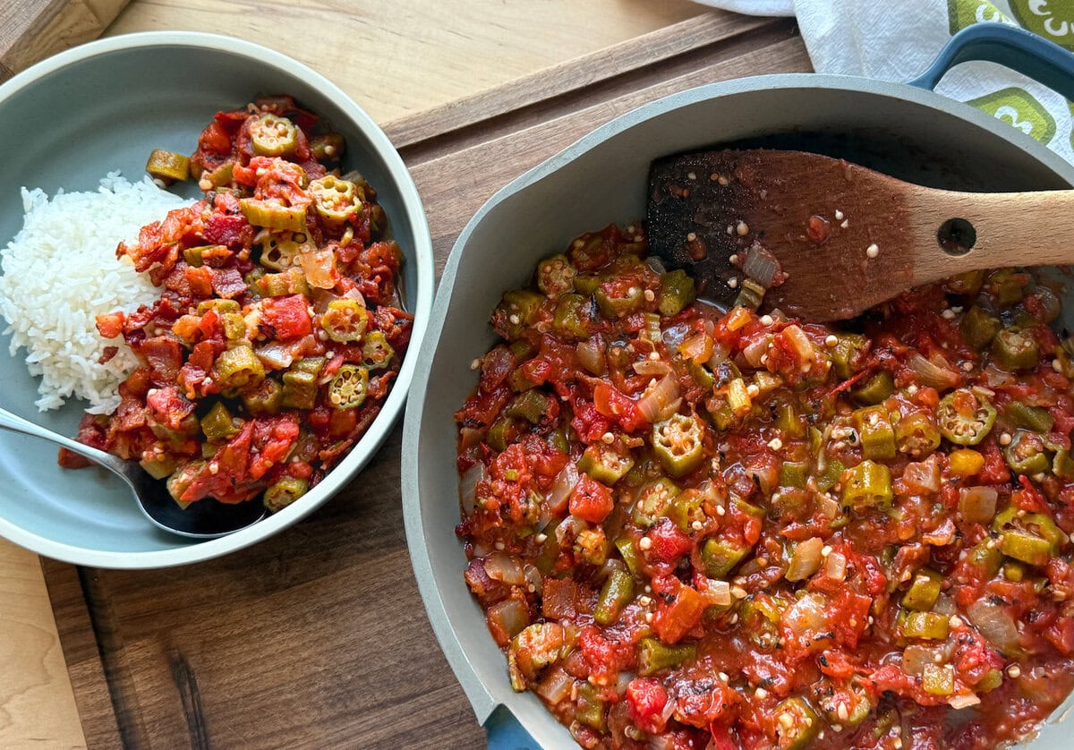 A delicious bowl of vegetable okra stew served alongside fluffy white rice, featuring vibrant tomatoes and tender okra pieces in a rustic setting.