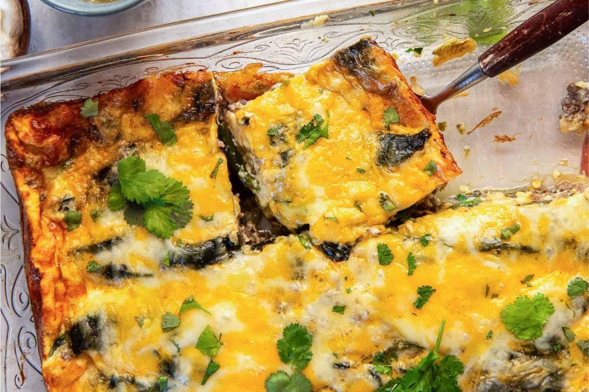 A close-up of a cheesy vegetable casserole topped with fresh cilantro, showcasing a golden crust and layers of ingredients.