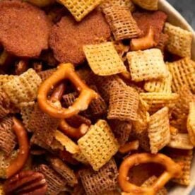 A close-up view of a bowl filled with a flavorful mix of Chex cereal, pretzels, and seasoned snacks.