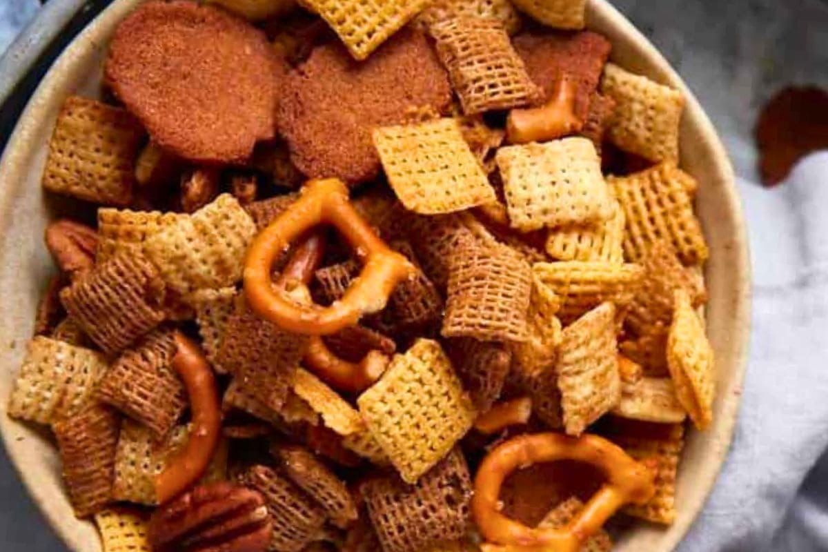A close-up view of a bowl filled with a flavorful mix of Chex cereal, pretzels, and seasoned snacks.