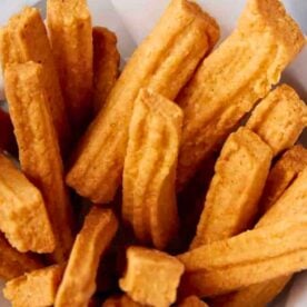 A close-up view of freshly made golden churros, arranged in a basket with a crisp texture.