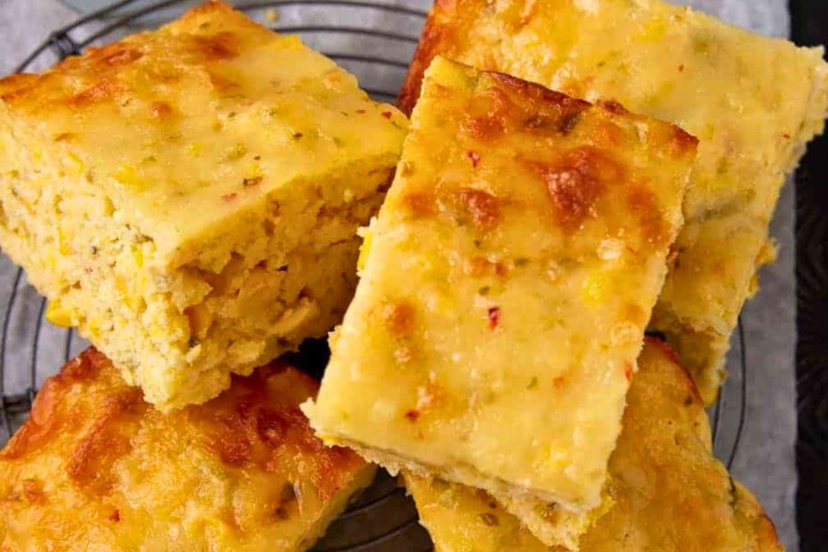 Deliciously baked cornbread squares arranged artfully on a wire rack, showcasing a golden-brown crust and soft interior.
